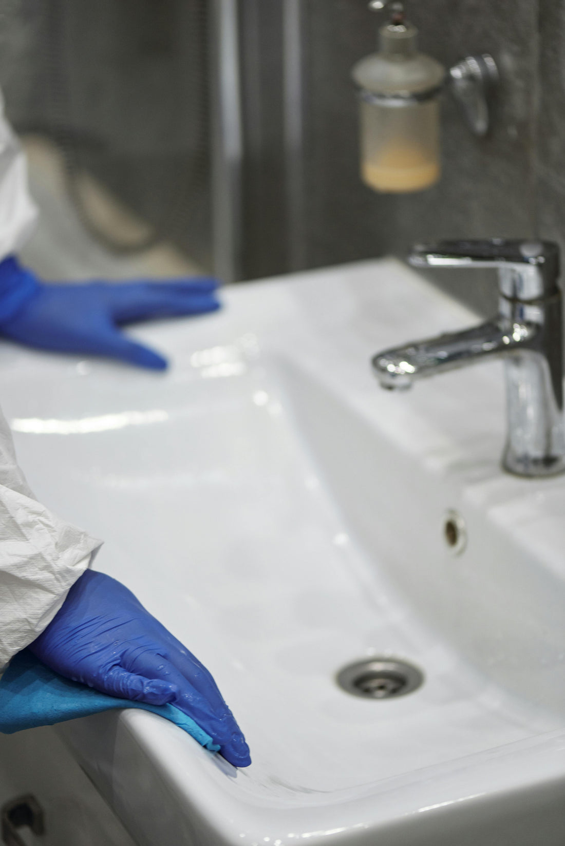 Persoon die badkamer schoonmaakt met doekje en reinigingsmiddel voor een frisse en hygiënische ruimte
